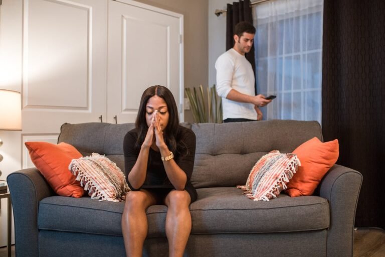 A opset Woman Sitting on the Sofa While a Man is Standing at the Back with phone